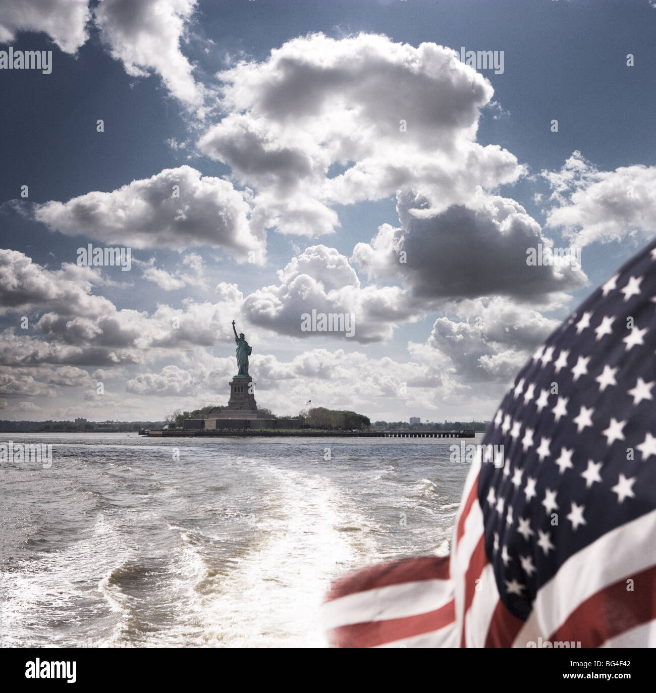 View of Statue of Liberty from rear of bot with Stars and Stripes flag, New York, United States of America, North America Stock Photo