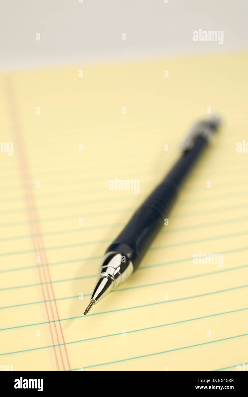 Blue mechanical pencil on a yellow legal pad. Focus on the tip of the pencil. Stock Photo