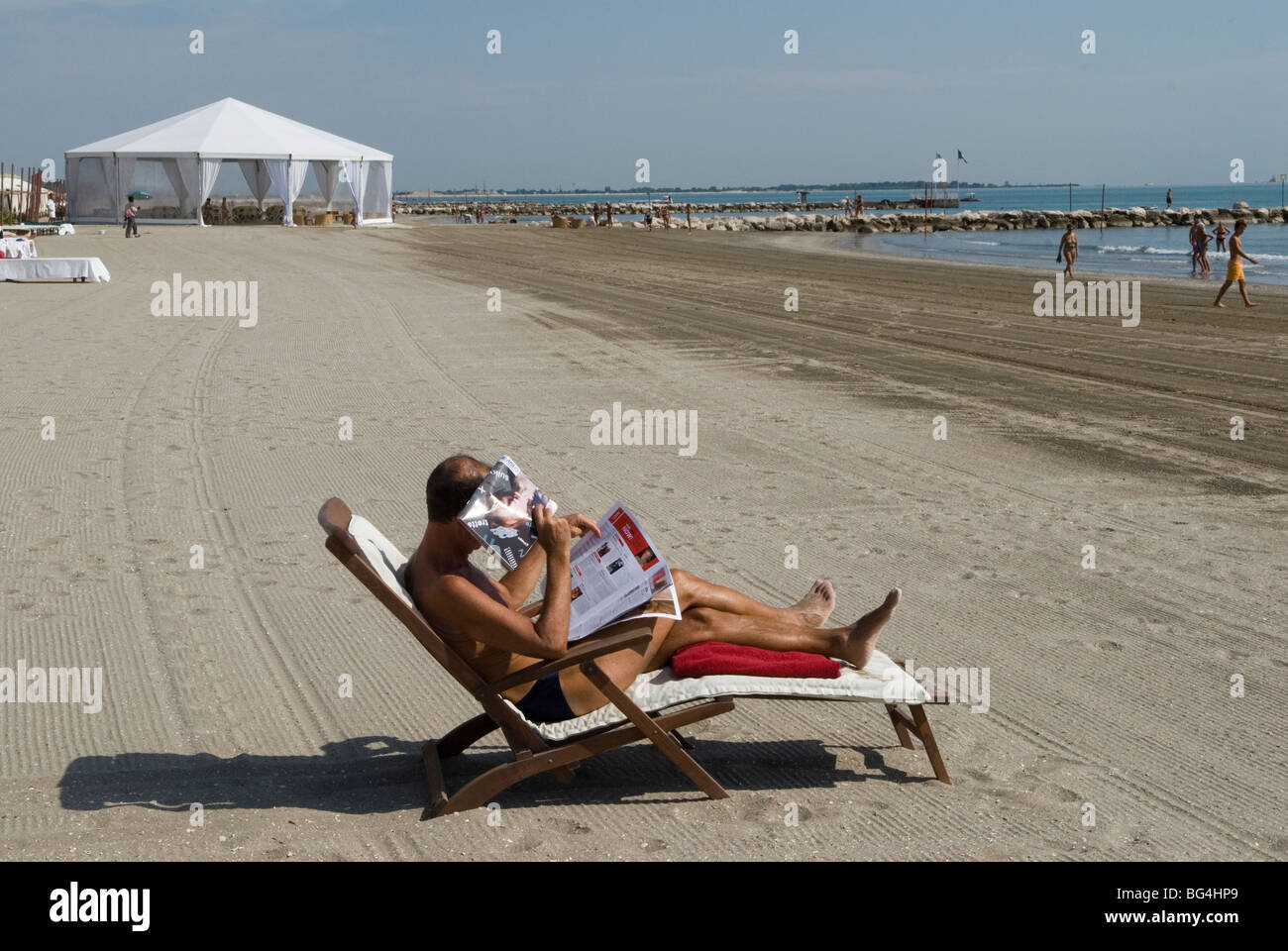Italian holidaymaker, lone male on the beach, using a newspaper as a sun shield Venice Lido beach Italy. 2000s. HOMER SYKES Stock Photo