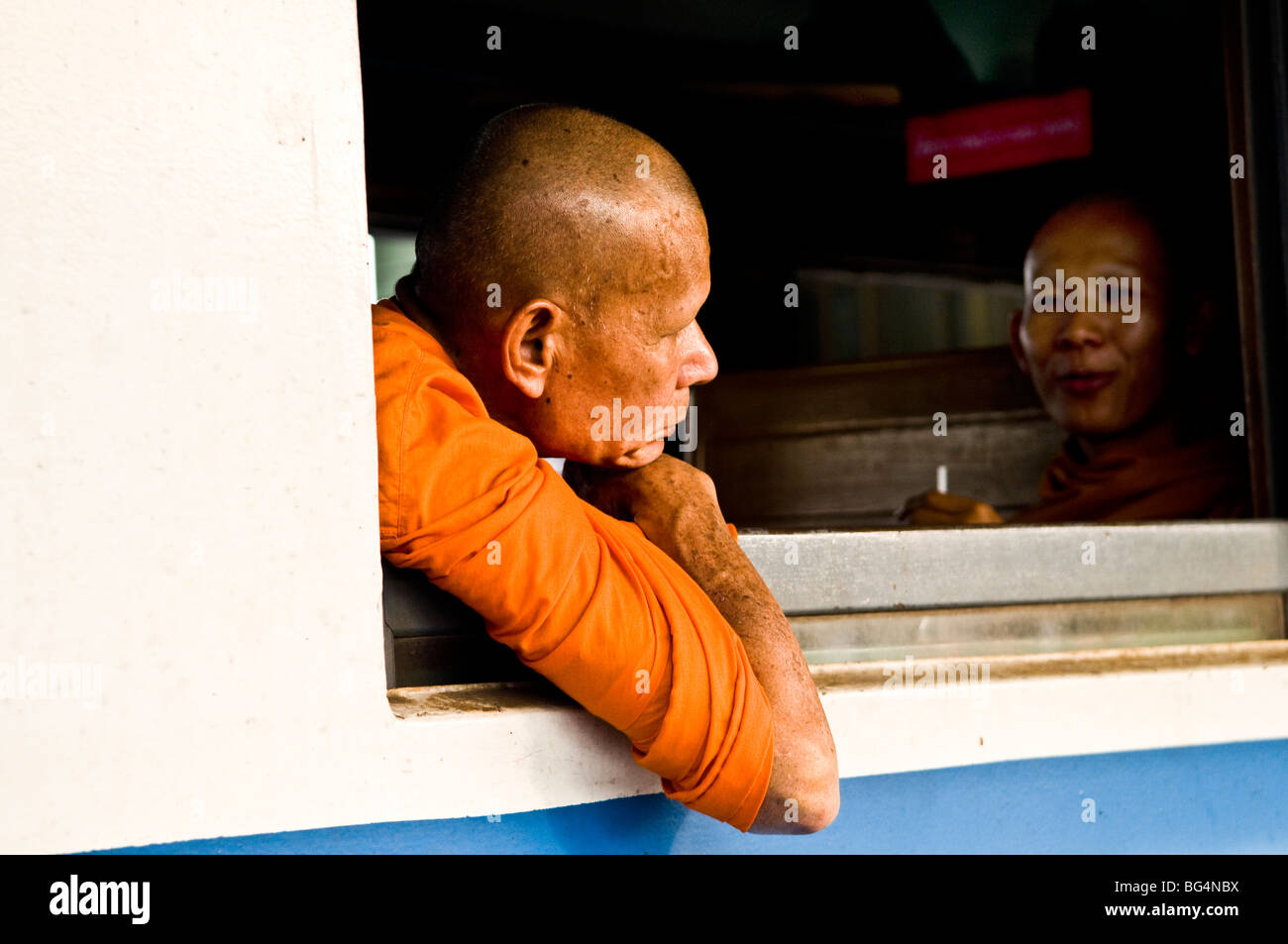 Waiting for the journey to begin. Buddhist monks sit in a local Thai train. Stock Photo