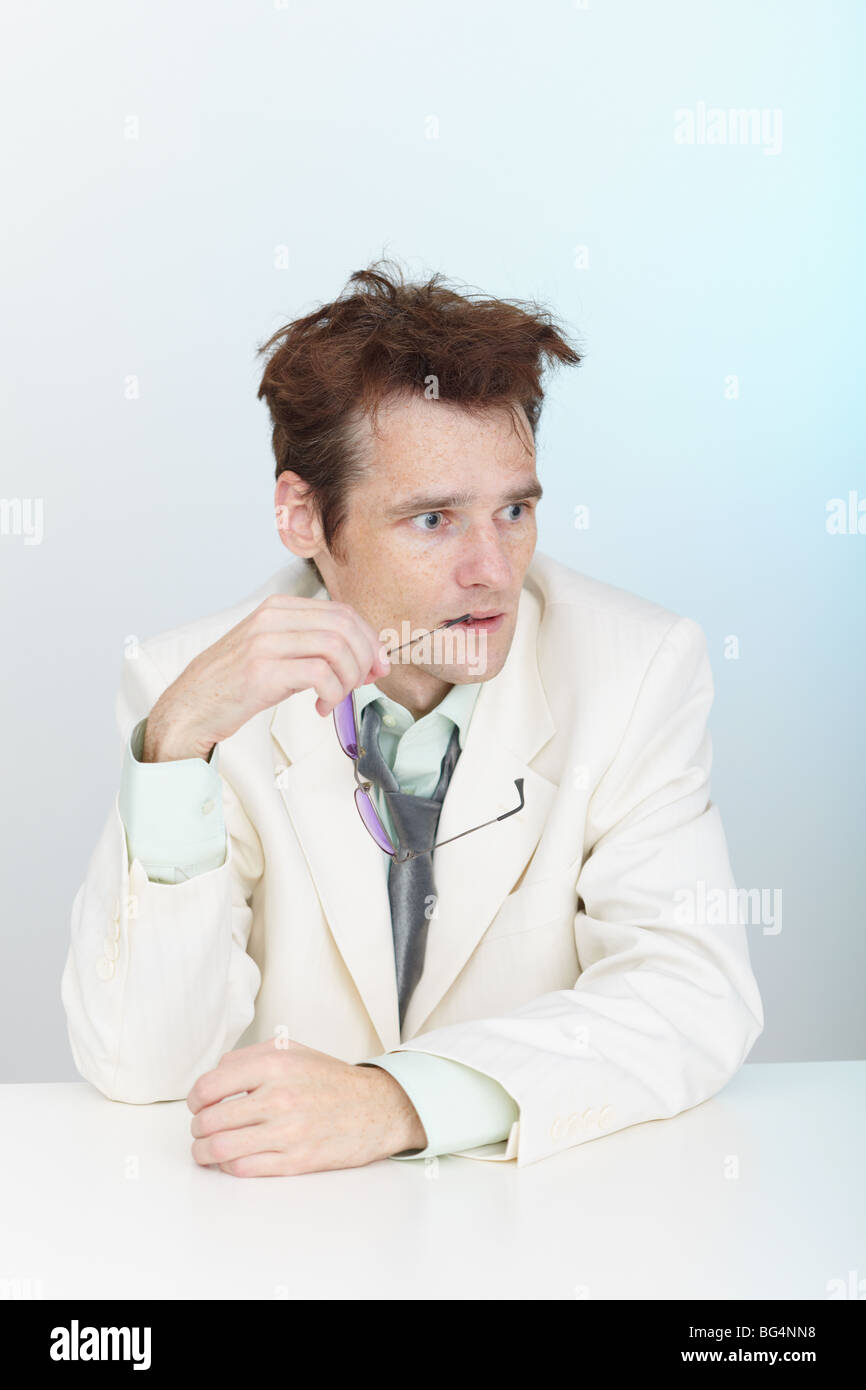 The confused tousled man sits at a table Stock Photo