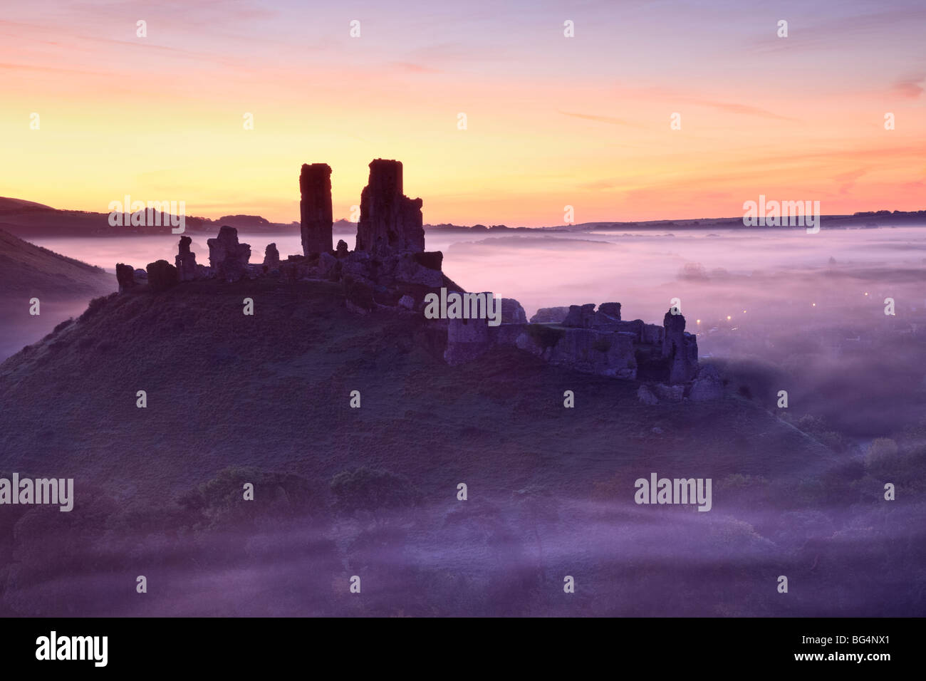 Corfe Castle, Dorset, UK, rising from the mist in autumn at sunrise Stock Photo