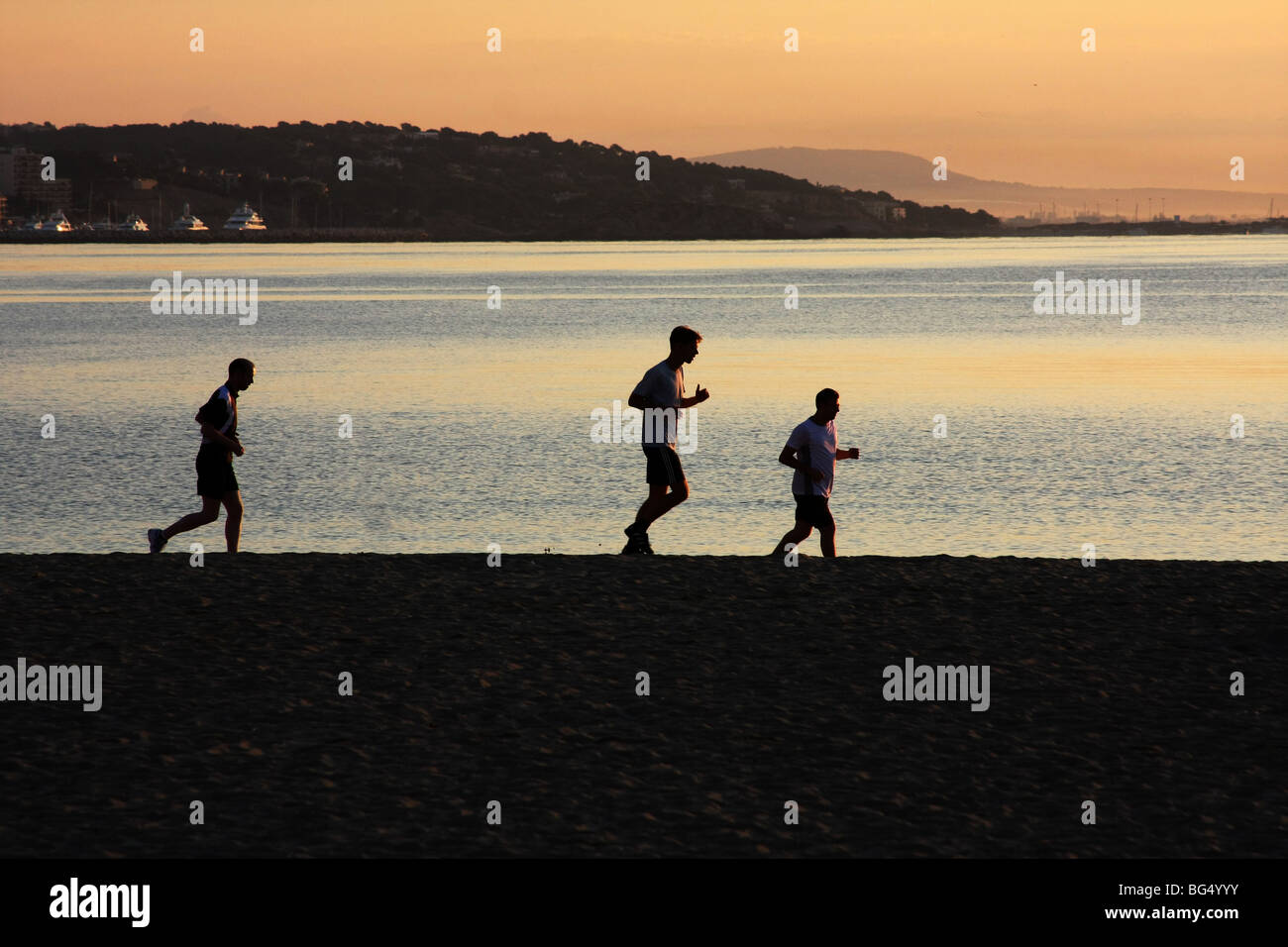 Joggers on the beach in Majorca before sunrise in silhouette. Stock Photo