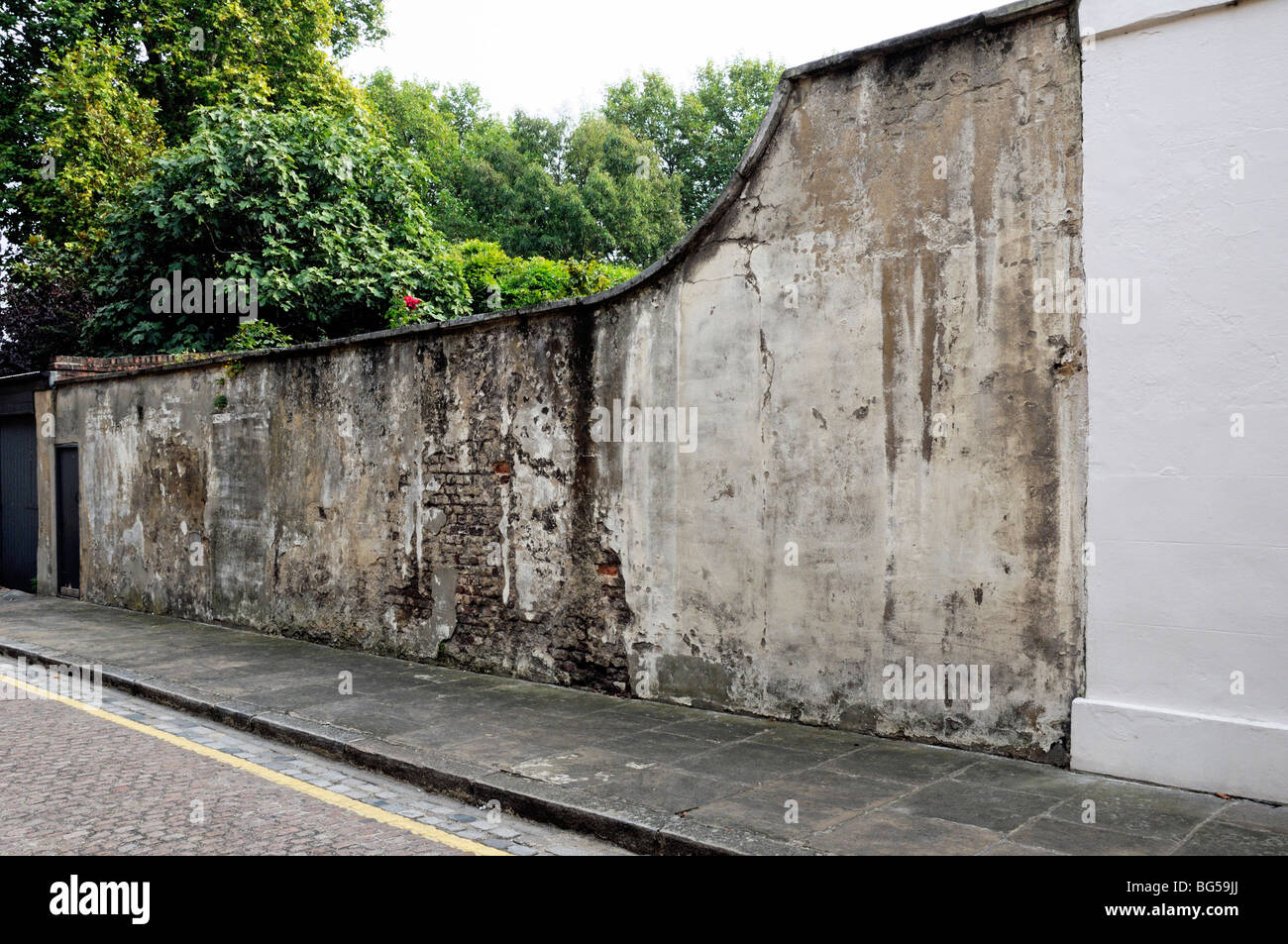 Old distressed brick and rendered garden wall Limehouse East London England UK Stock Photo