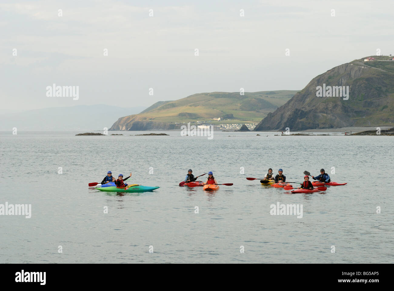 Canoeists off Aberystwyth, Wales with Clarach village behind. Stock Photo