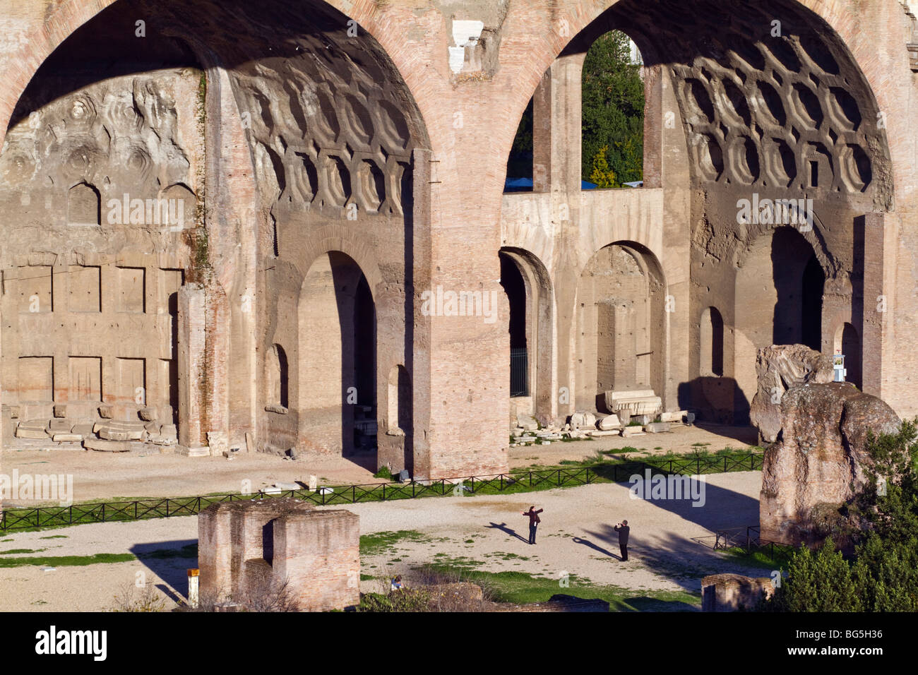 A tourist in the Roman Forum gestures to emphasize the magnitude of the Basilica of Maxentius and Constantine. Stock Photo