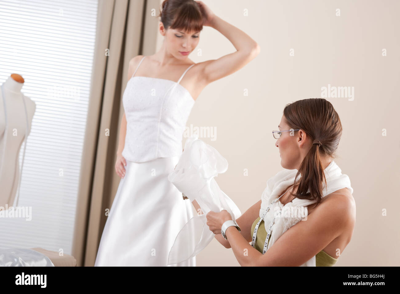 Fashion model fitting white wedding dress in successful professional woman fashion designer