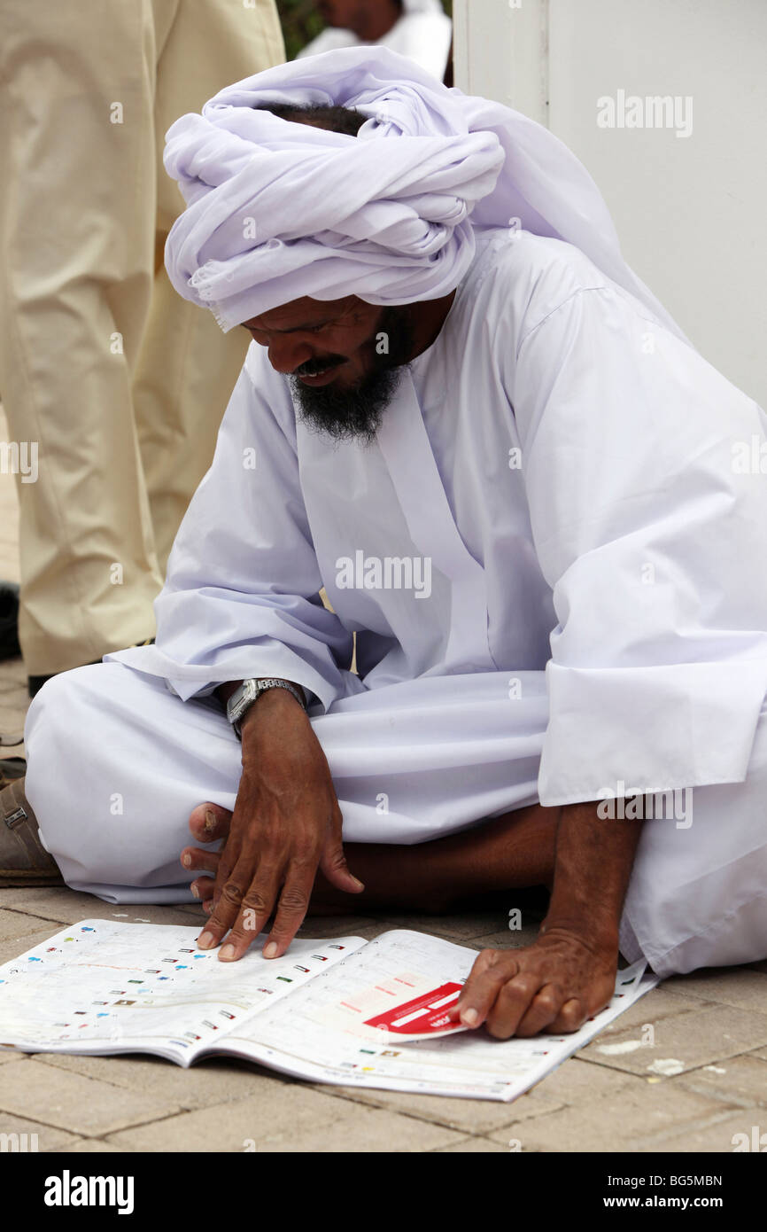 An Arab reading a horse race programme, Dubai, United Arab Emirates Stock Photo