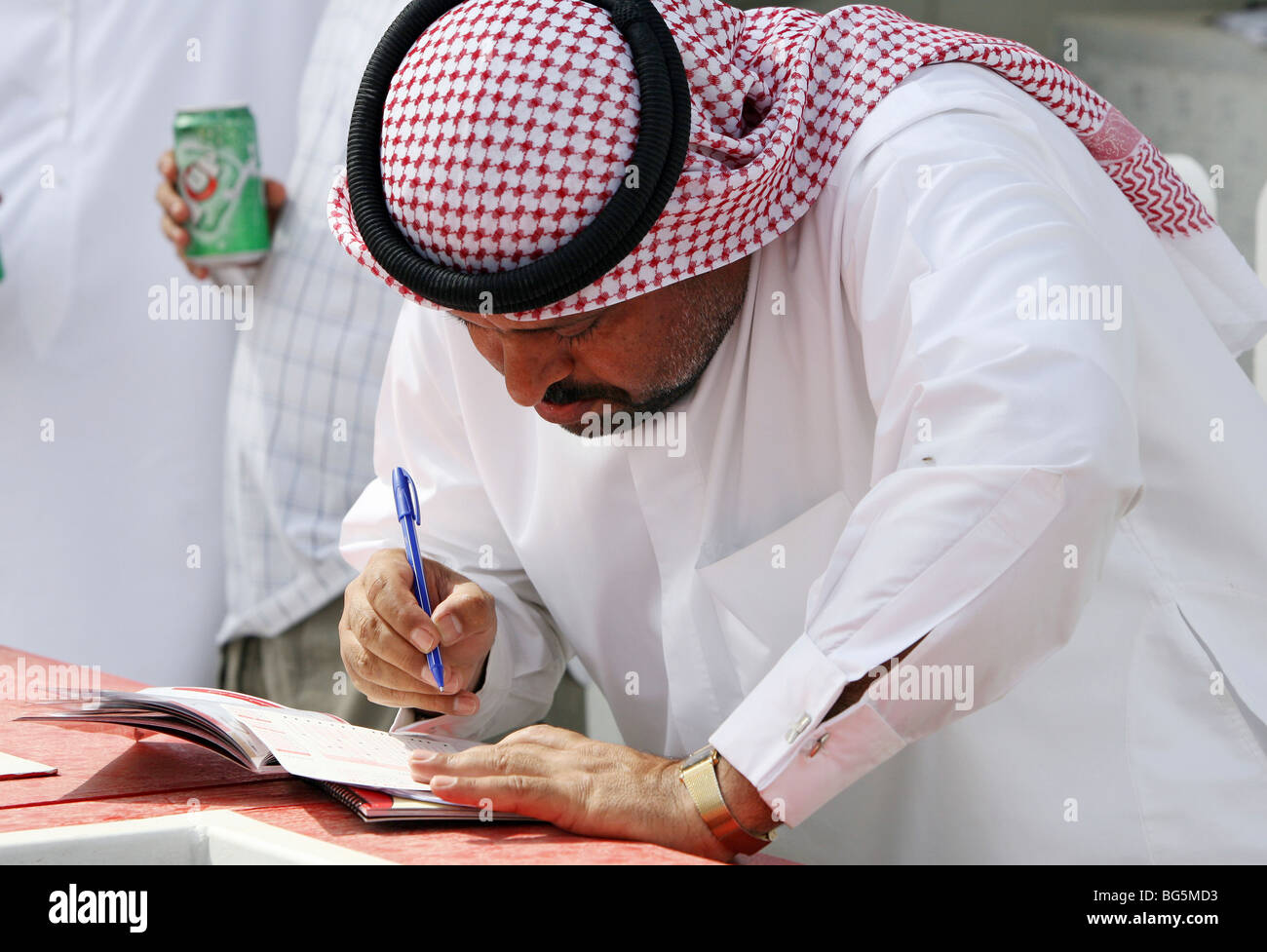 A man filling out a bet ticket, Dubai, United Arab Emirates Stock Photo