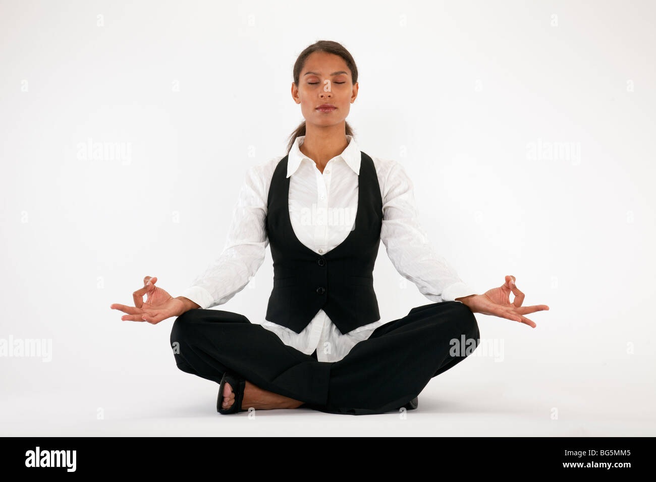 Young woman sitting cross legged and meditating. Horizontally framed shot. Stock Photo