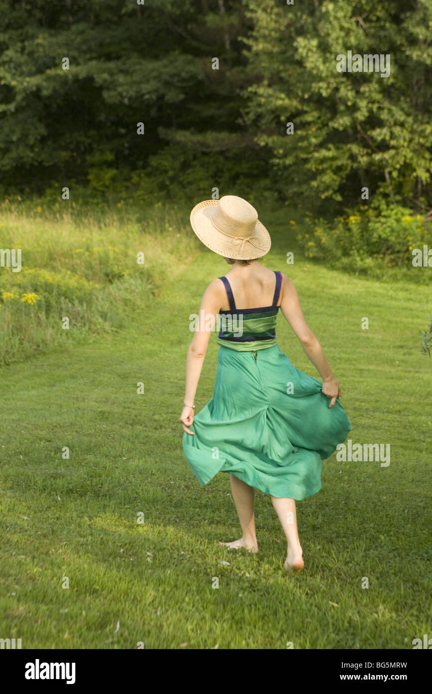 Young woman in a straw hat walking through a meadow Stock Photo