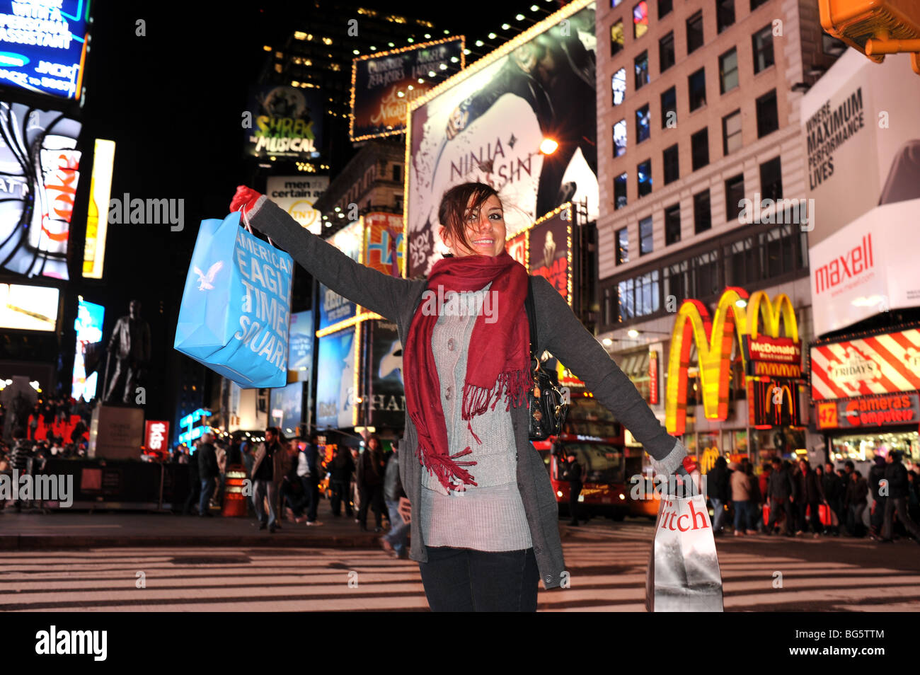 Young woman female happy smiling with bags in Times Square New York USA Stock Photo