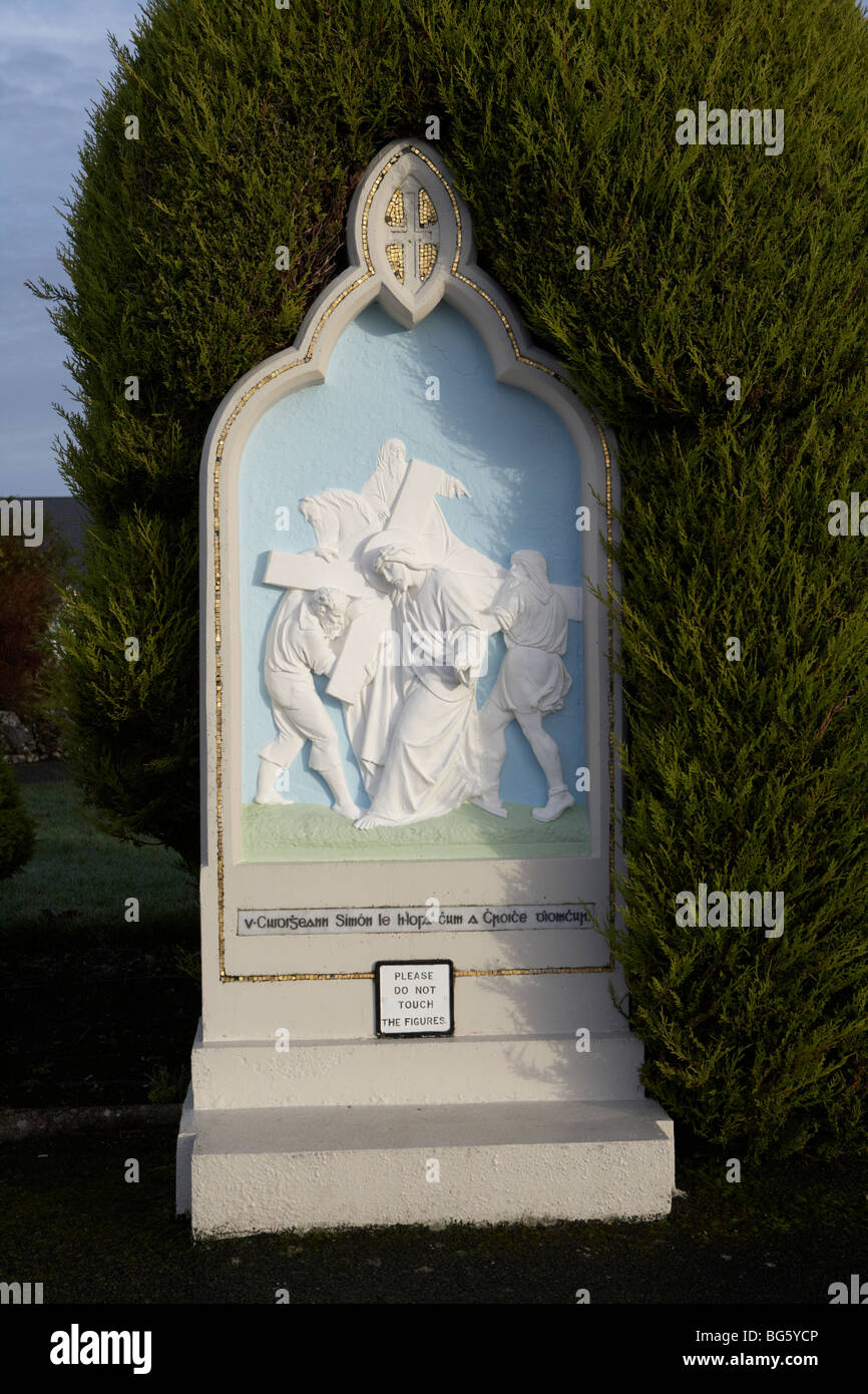 simon of cyrene carries the cross the 5th station of the cross with irish gaelic writing at knock marian shrine county mayo Stock Photo