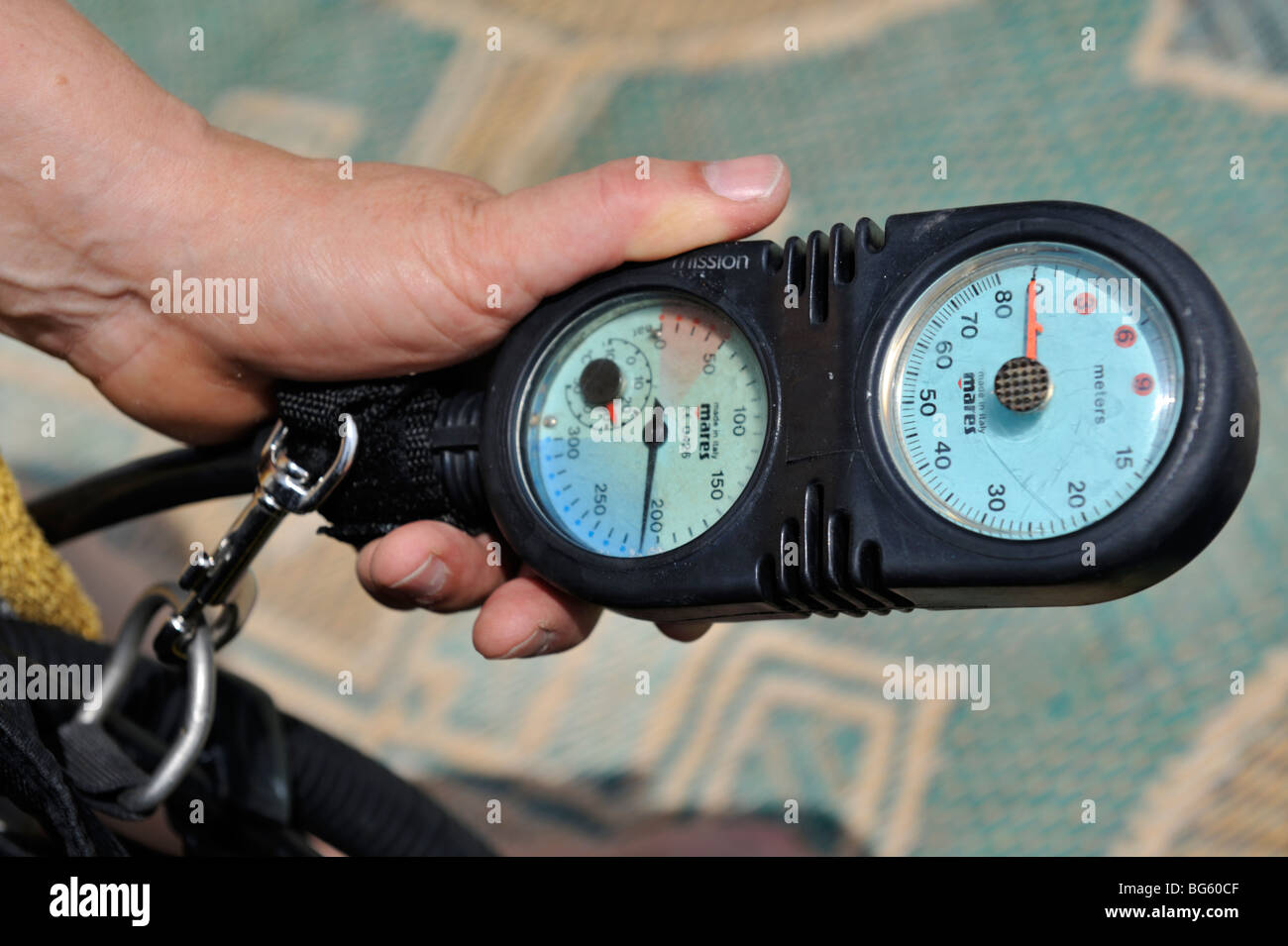 Hand holding scuba diving console with pressure and depth gauge in it Stock Photo