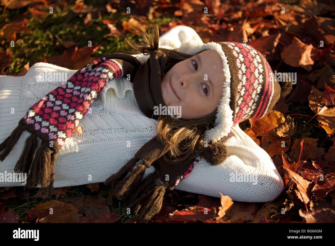 Happy young girl laying on pile of autumn leaves Stock Photo - Alamy