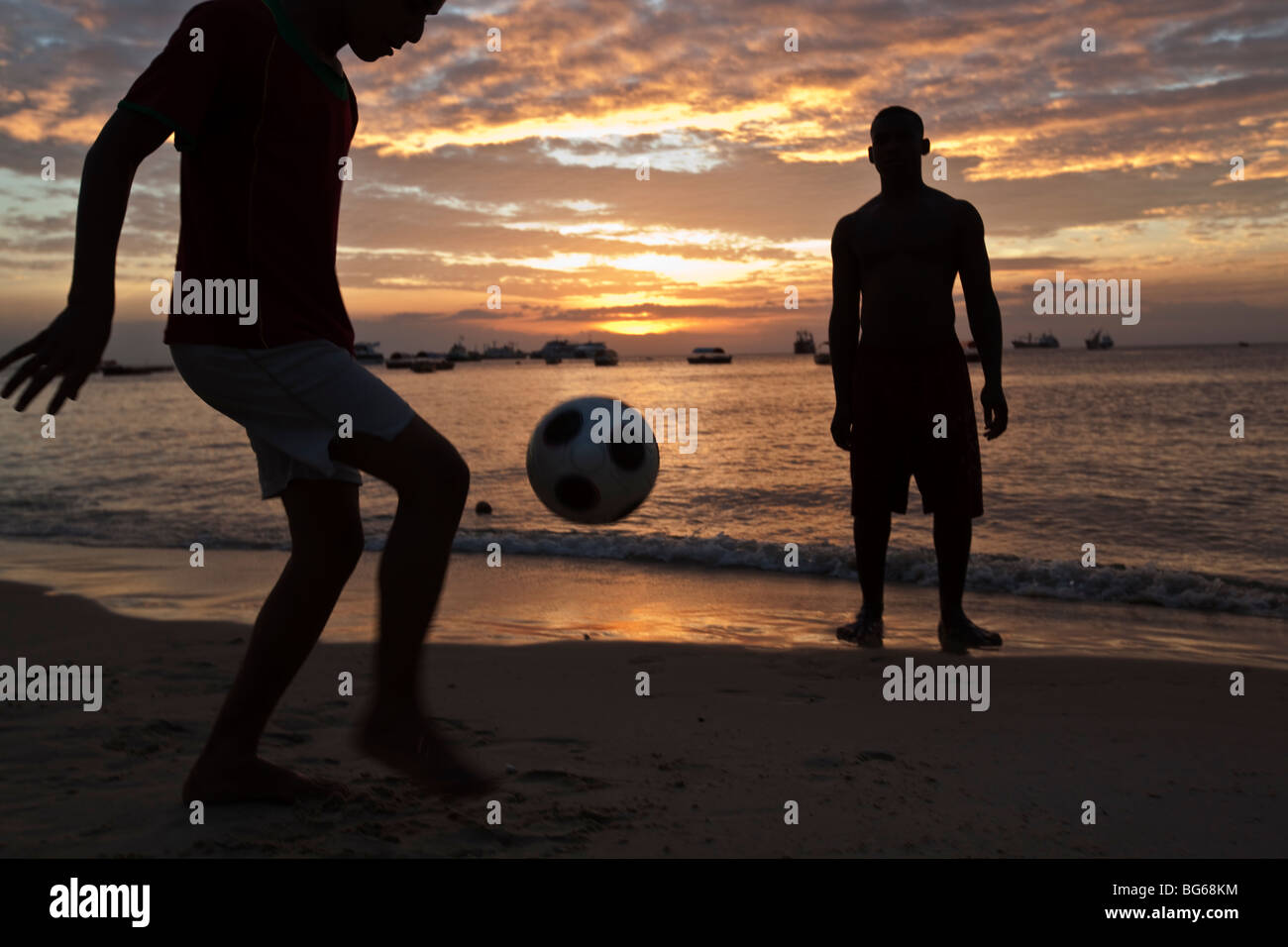 Youths play football at sunset along the shores of the Indian Ocean in Zanzibar, Tanzania. Stock Photo