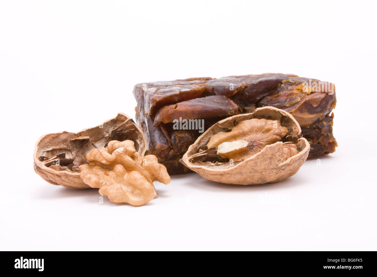 Block of pressed, dried dates with cracked open walnut halfs isolated against white background. Stock Photo