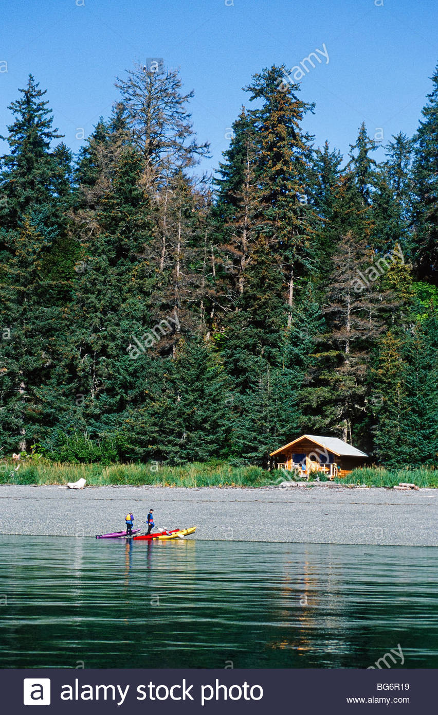 Alaska Kachemak Bay Kayakers Pull Up On A Beach Log Cabin Stock