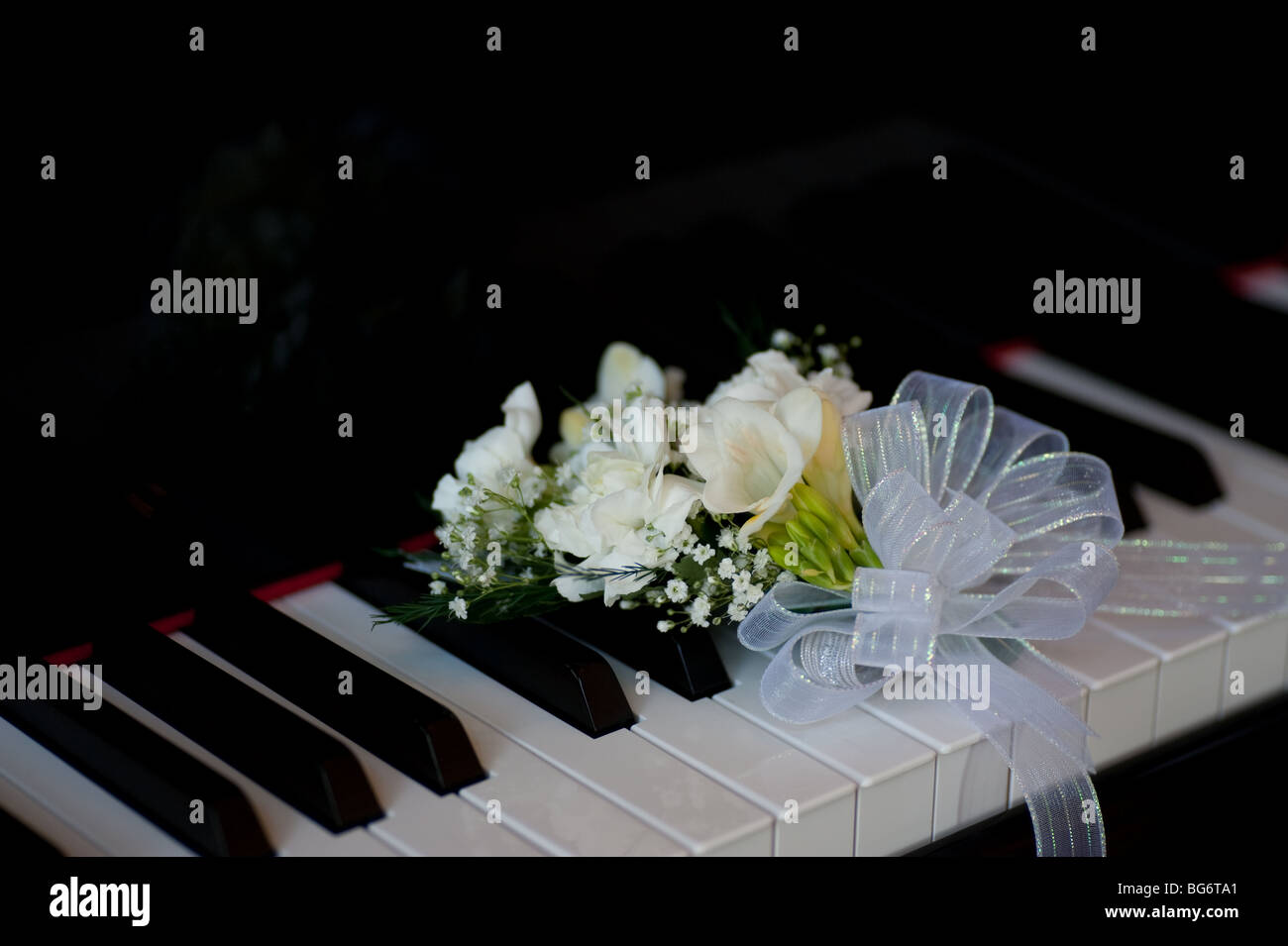 Corsage sitting on grand piano keyboard Stock Photo