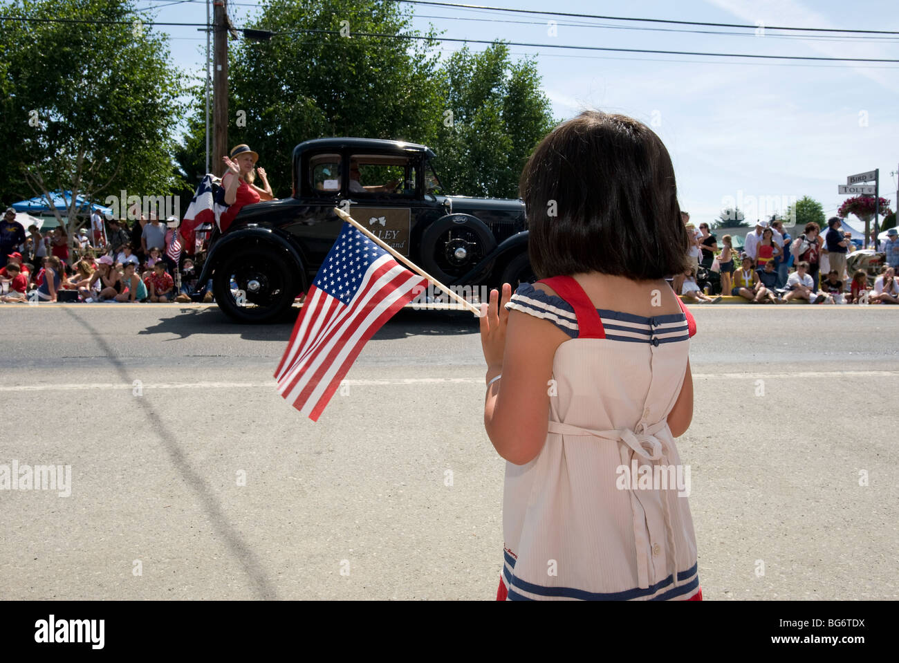 Girl holding American flag during 4th of July parade. Stock Photo