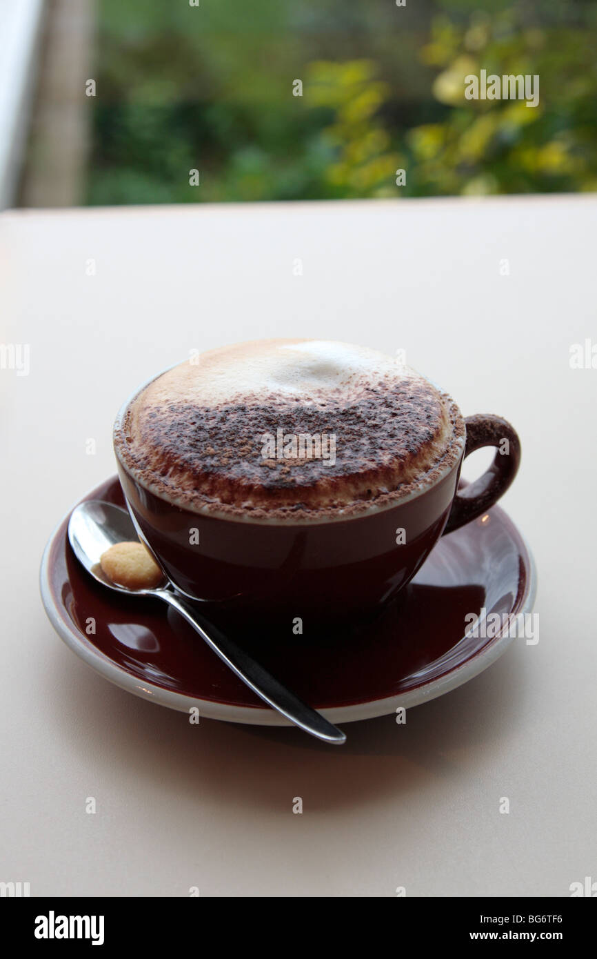 Cappuccino with a chocolate cross on top in a blue cup and saucer on a blue table Stock Photo