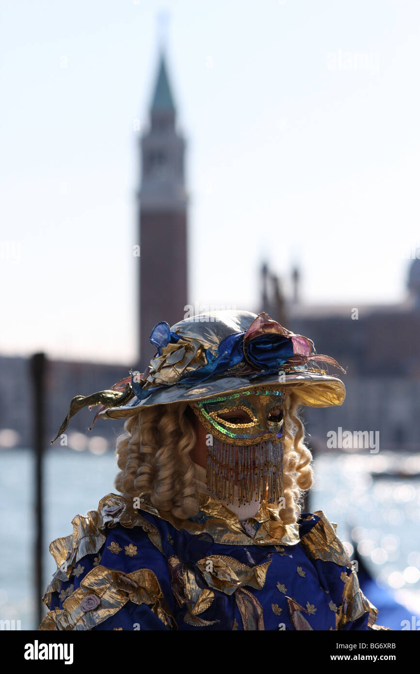 Venetian woman wearing a mask and costume with St Mark's Campanile in the background Stock Photo