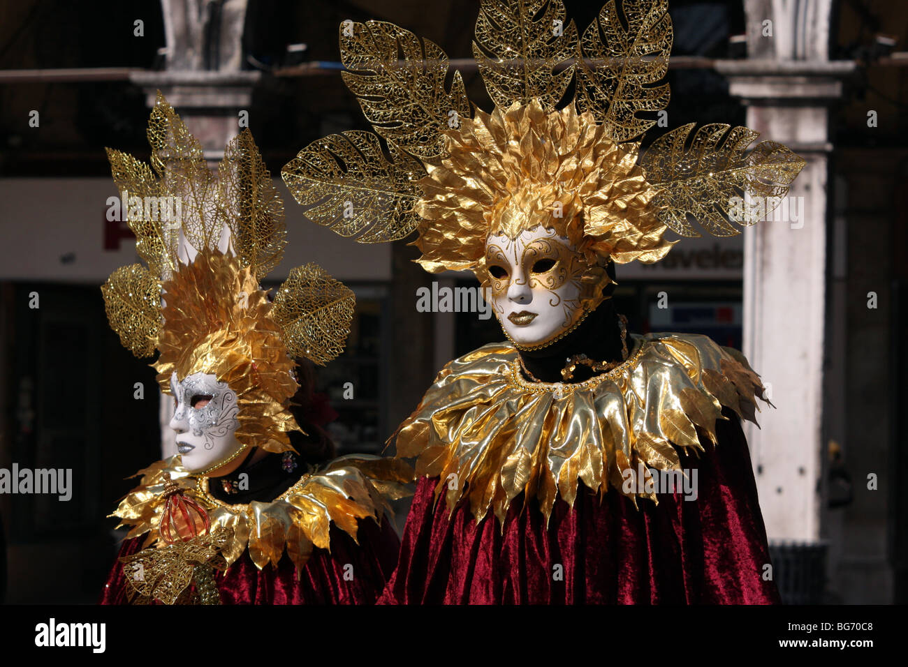 Close-up of a Venetian couple wearing white masks and red and gold costumes in Venice Carnival 2009 Stock Photo
