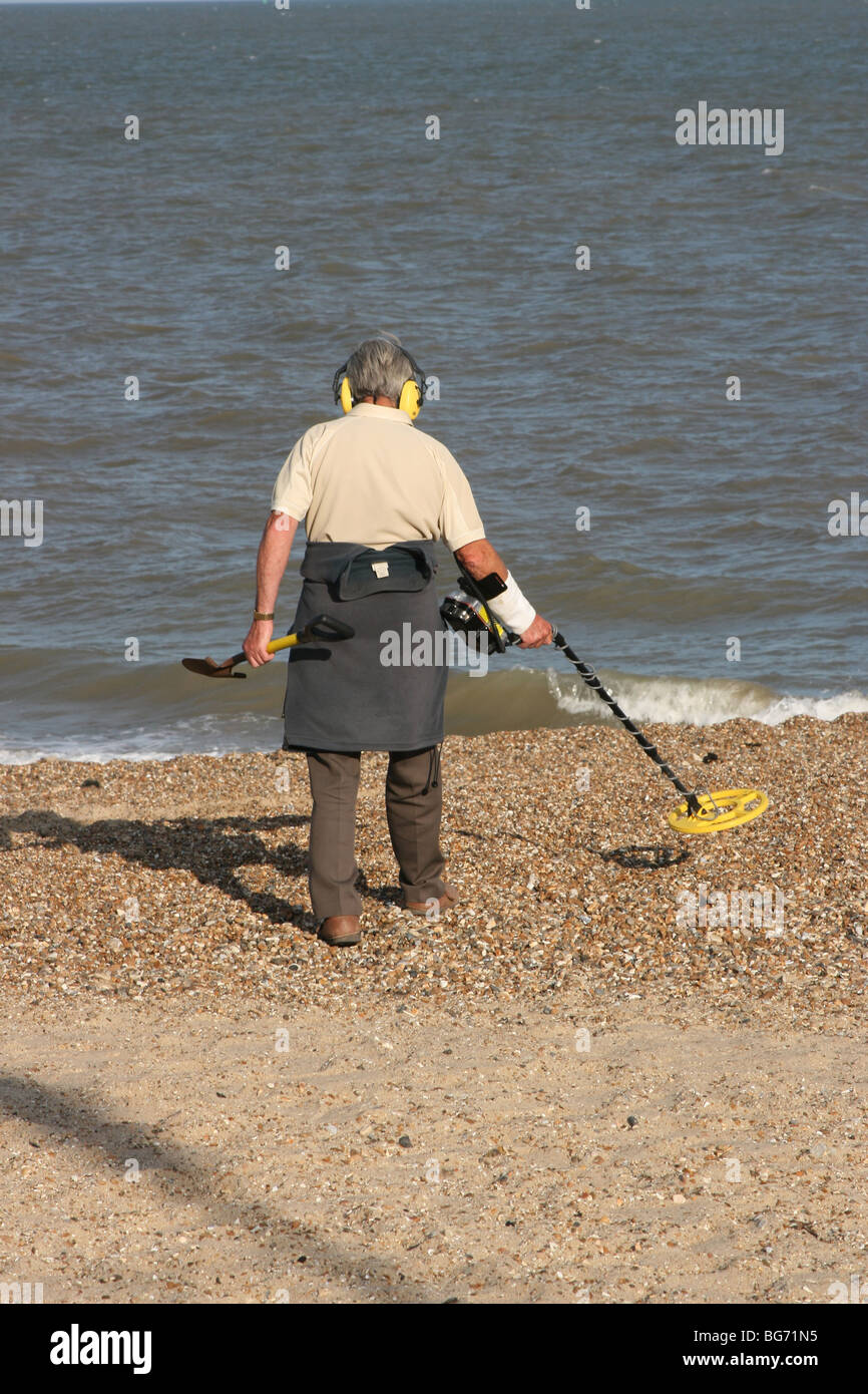 Man walking on beach with metal detector Stock Photo - Alamy