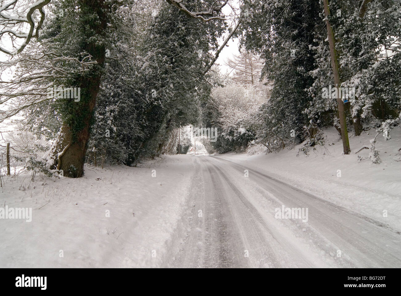 Small A road in the english countryside of Hampshire after a heavy snowfall with tyre tracks in the snow Stock Photo