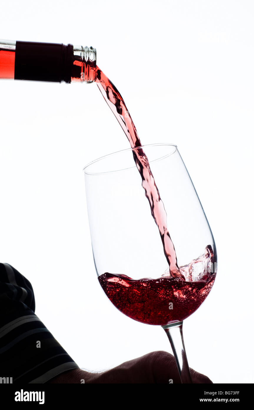 red wine being poured into wineglass from bottle Stock Photo