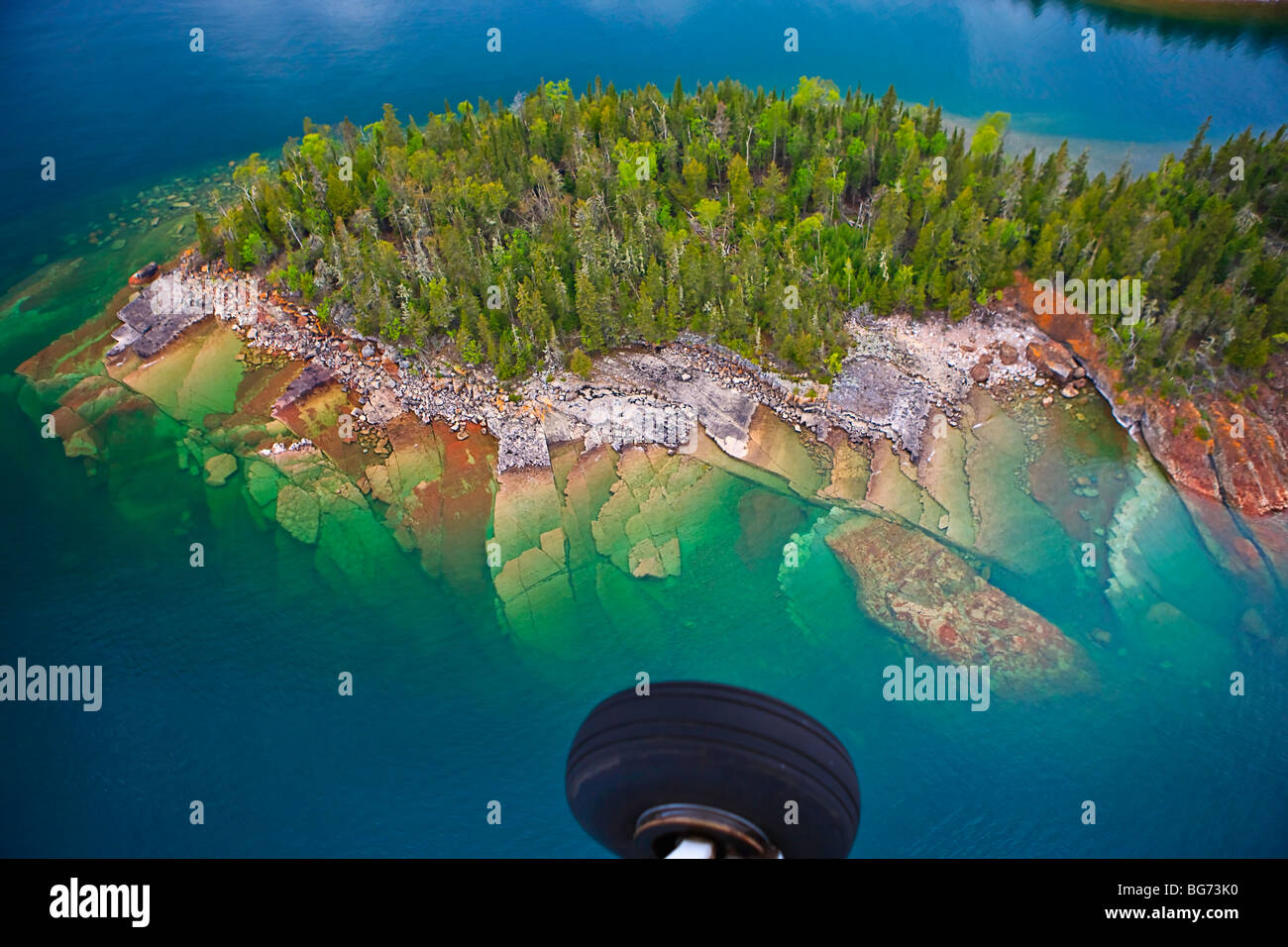 Aerial view of small rocky Islands with a clear view through the water to the rocks below in Lake Superior during a flight from  Stock Photo