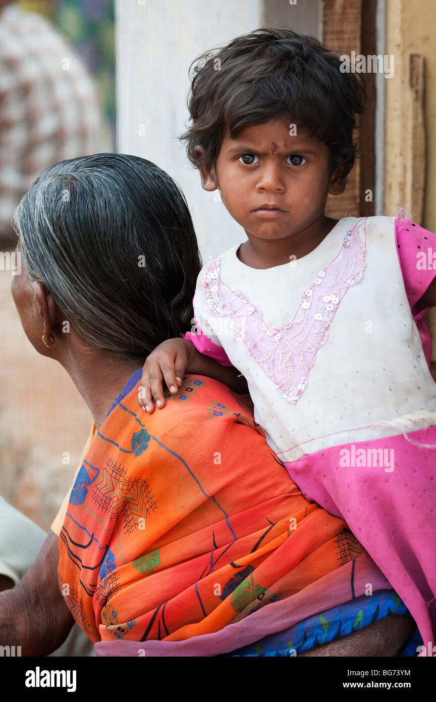 Indian toddler leaning on her grandmother in the doorway of there house in a rural indian village. Andhra Pradesh, India Stock Photo