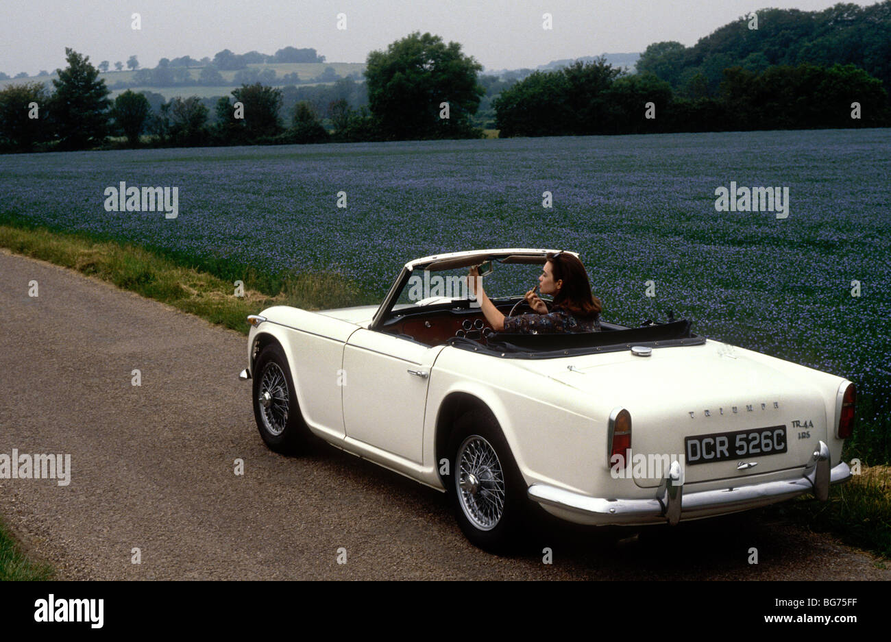 Woman checking her make up before driving off in a 1965 Triumph TR4 Stock Photo
