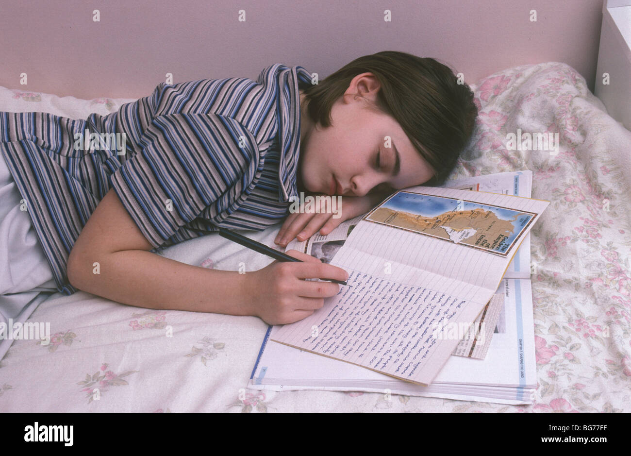 young girl doing her homework in bed and falling asleep Stock Photo Alamy