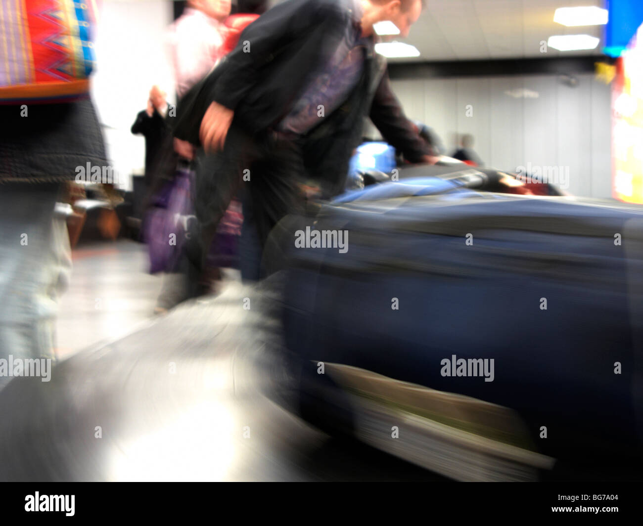 passengers collecting moving baggage reclaim carousel at belfast international airport uk motion blur Stock Photo