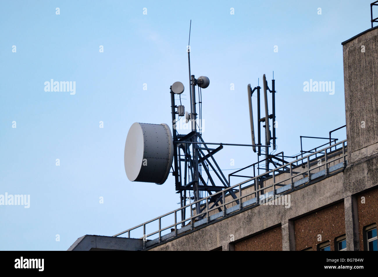 Microwave antenna on top of a telephone exchange beside cellular network antennas. Stock Photo