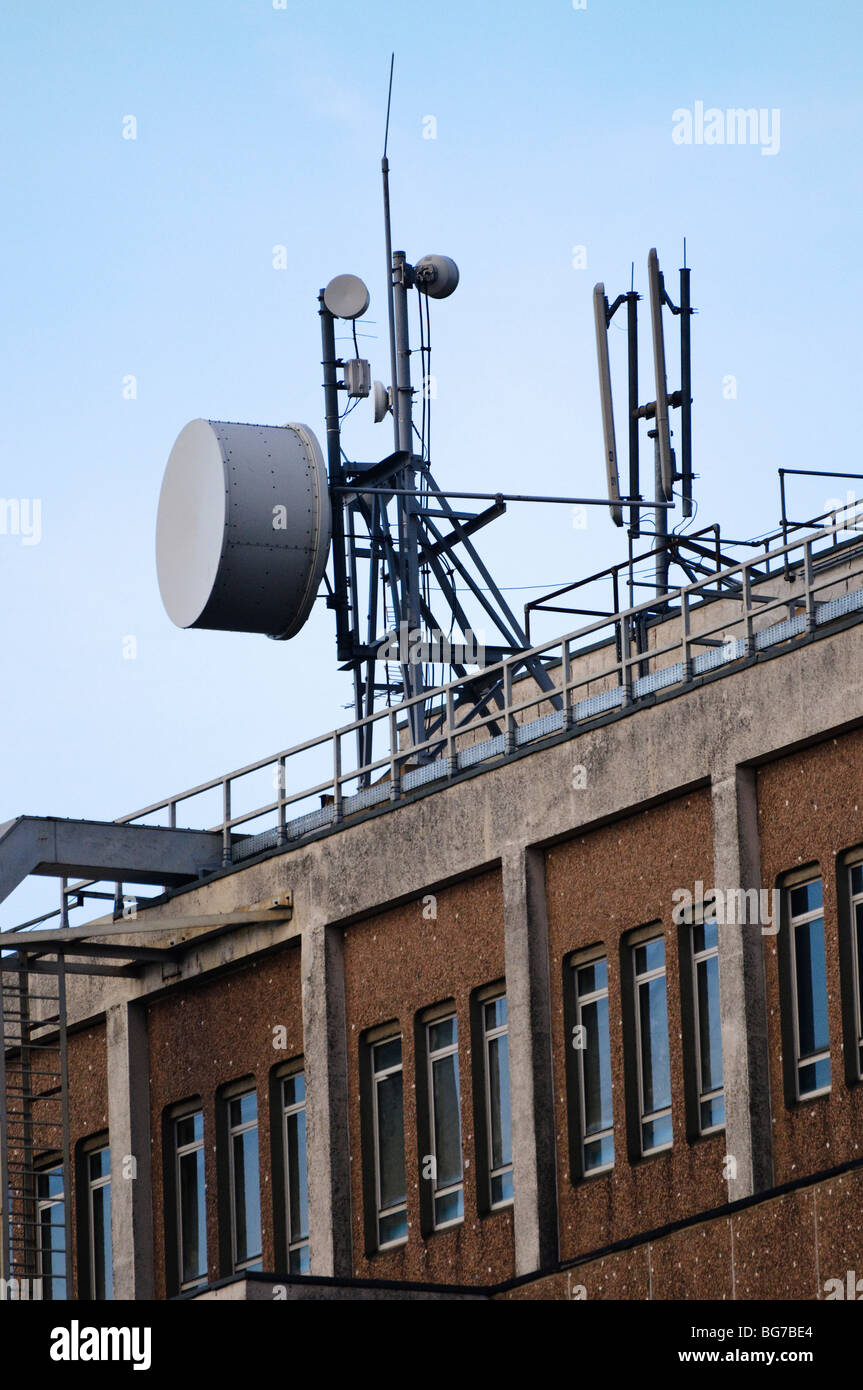 Microwave antenna on top of a telephone exchange beside cellular network antennas. Stock Photo