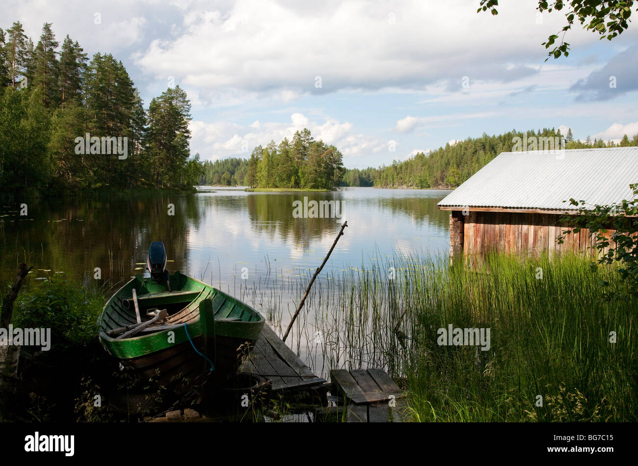 Old Finnish boathouse  , made of logs ,  and a wooden rowboat / skiff / dinghy at lake Etelä-Konnevesi shore , Finland Stock Photo