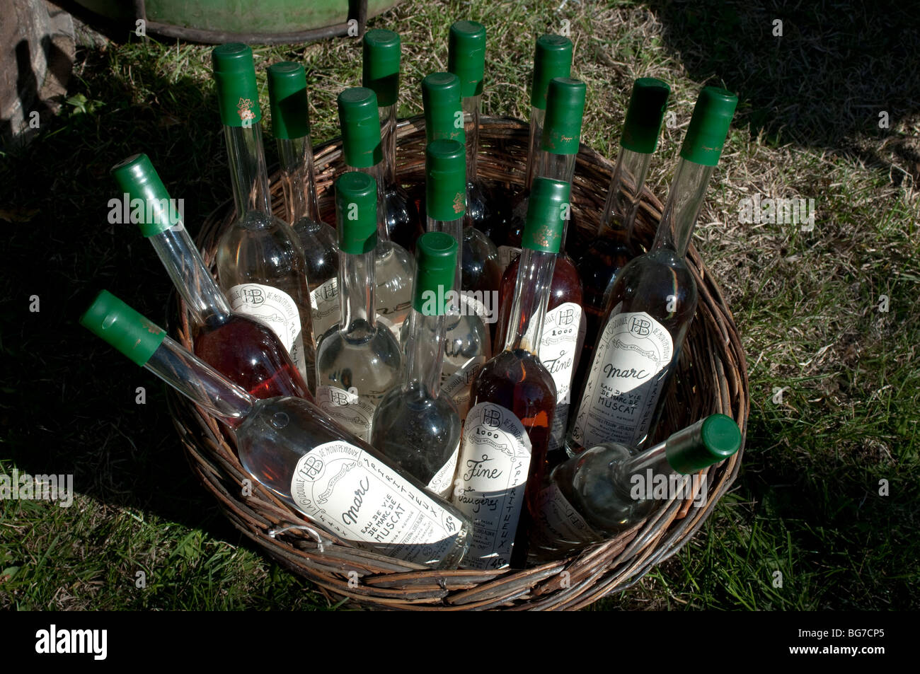 Bottles of traditionally distilled spirits in a basket, Market in Montoulieu, Herault, France Stock Photo