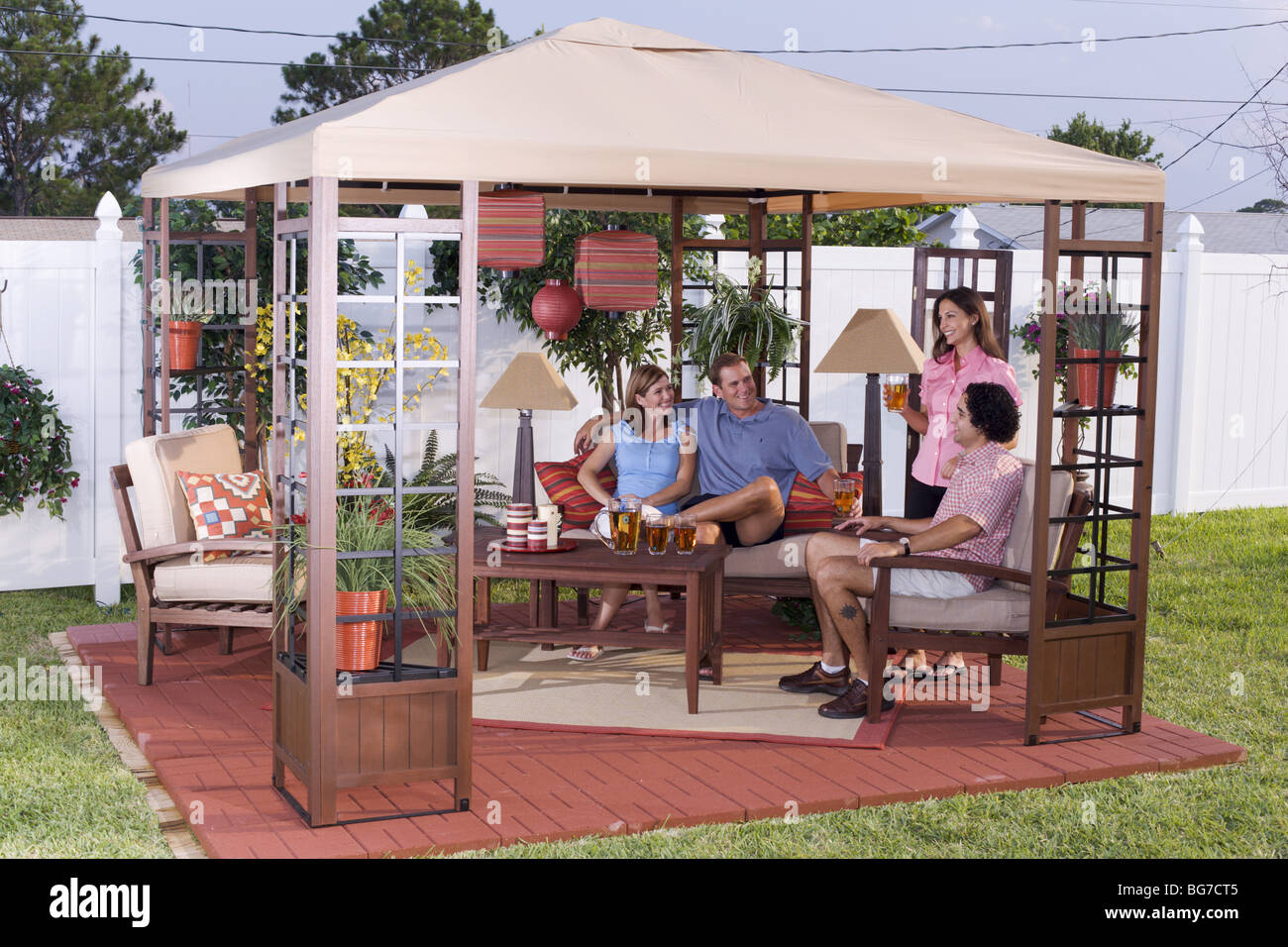 Young Couples Relaxing On Outside Deck Patio Home Exterior Stock