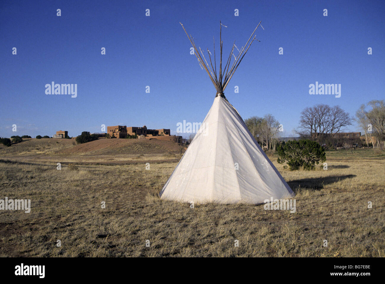 An Indian TeePee near a large adobe house in the high desert of the