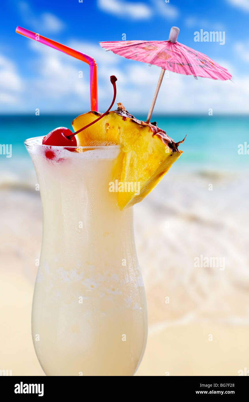 Pina colada drink in cocktail glass with tropical beach in background Stock Photo