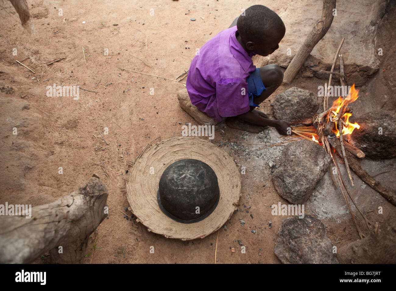A boy cooks over a fire in Acowa refugee camp in Amuria District, Uganda, East Africa. Stock Photo