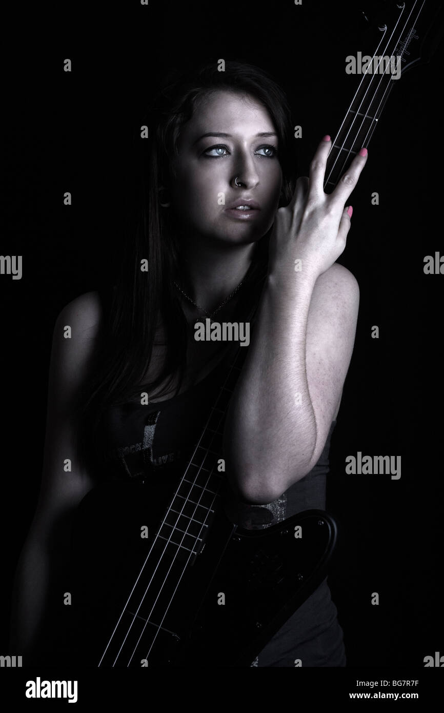 young female bass player in a grungy, dark setting Stock Photo