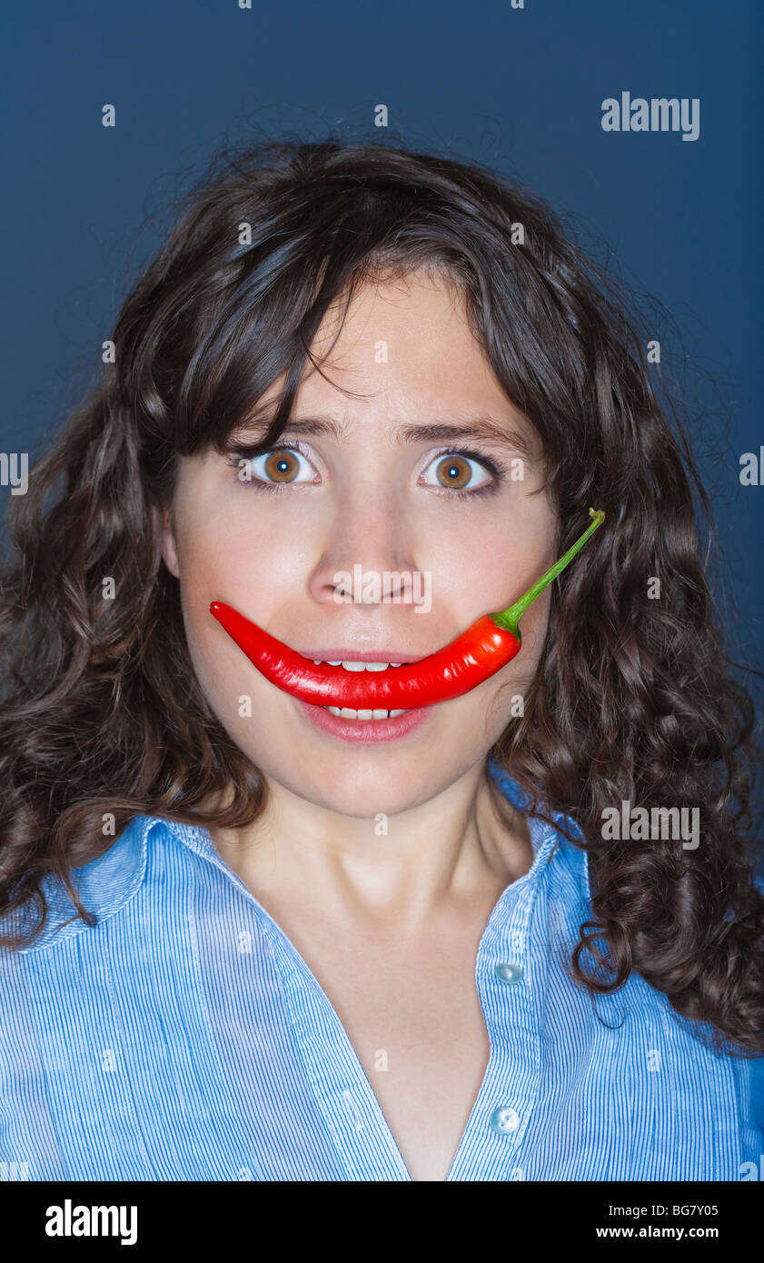 young brunette woman holding chili in her mouth Stock Photo