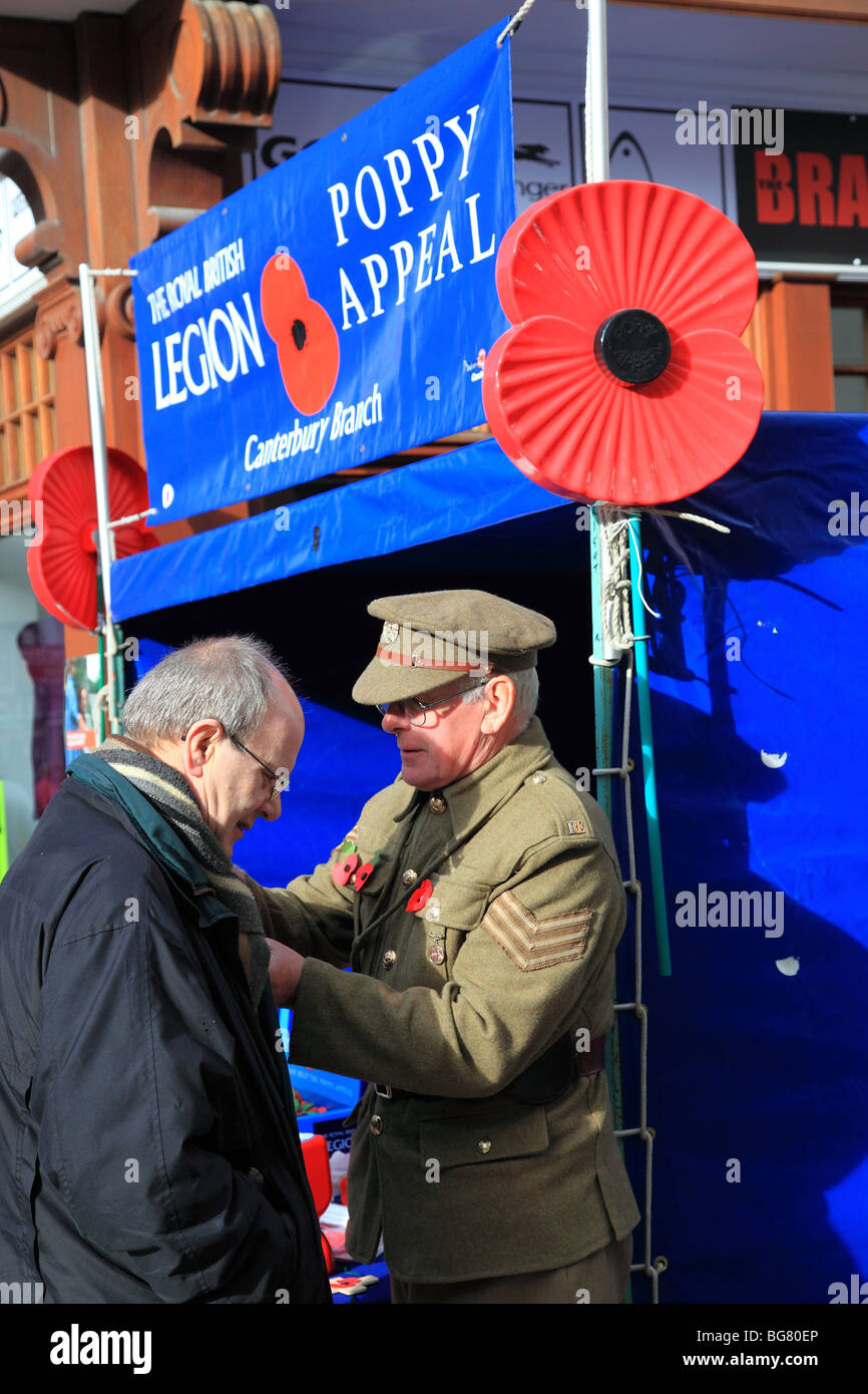 Man in the First World War uniform attaching a poppy to the coat of the old man in Poppy Appeal in Canterbury Stock Photo