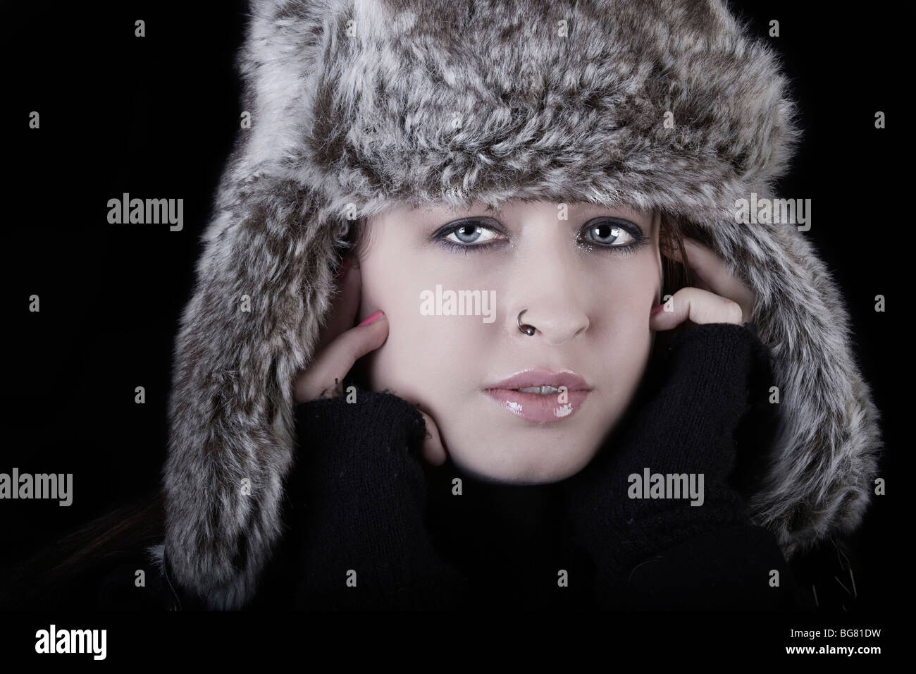 low key image of a beautiful young woman in a furry hat Stock Photo