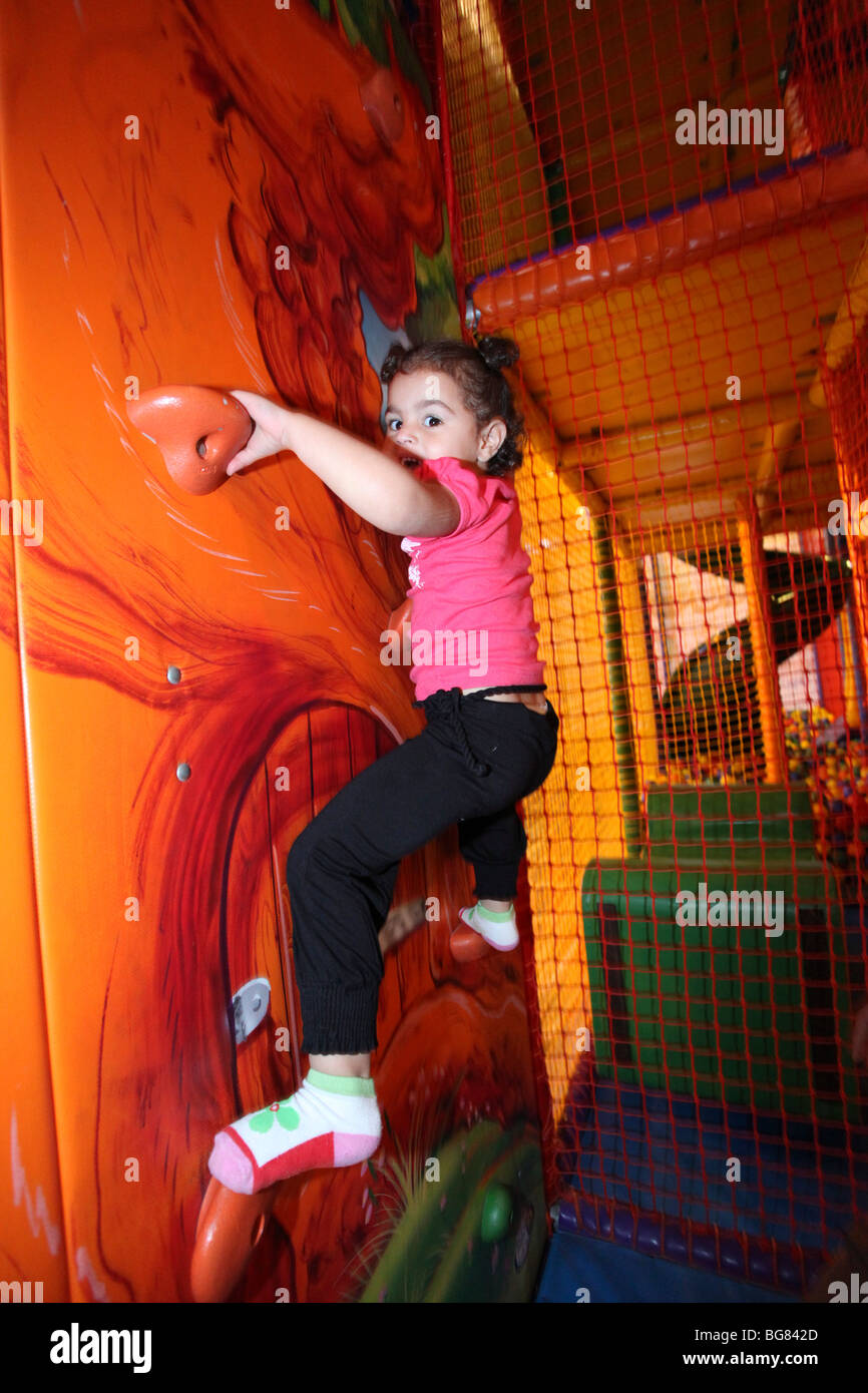 Indoor children's playground child climbs a wall Stock Photo