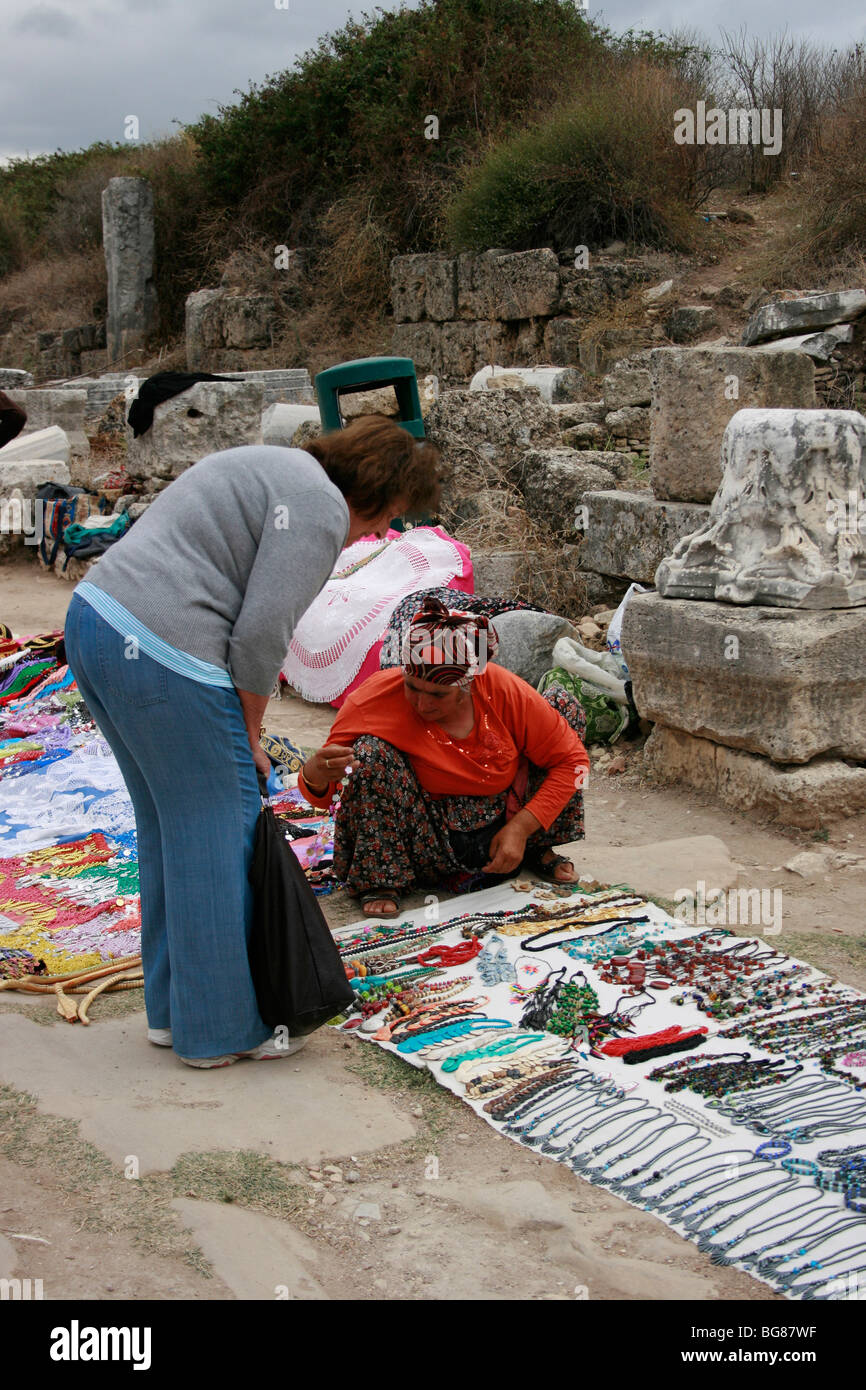 Turkish woman selling crafts and souvenirs to a female tourist in the ancient city of Perge Stock Photo