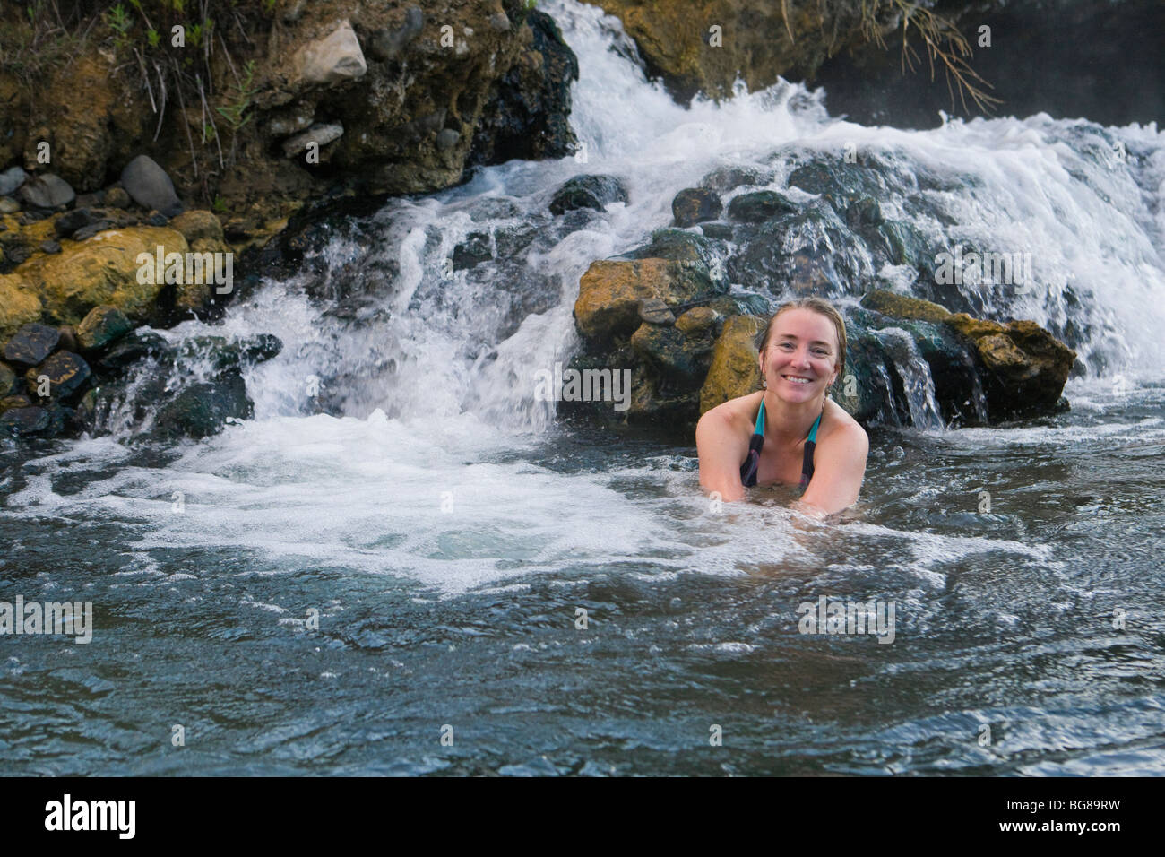 A smiling woman relaxing in The Boiling River section of the gallatin River, Yellowstone National Park, Wyoming, USA. Stock Photo